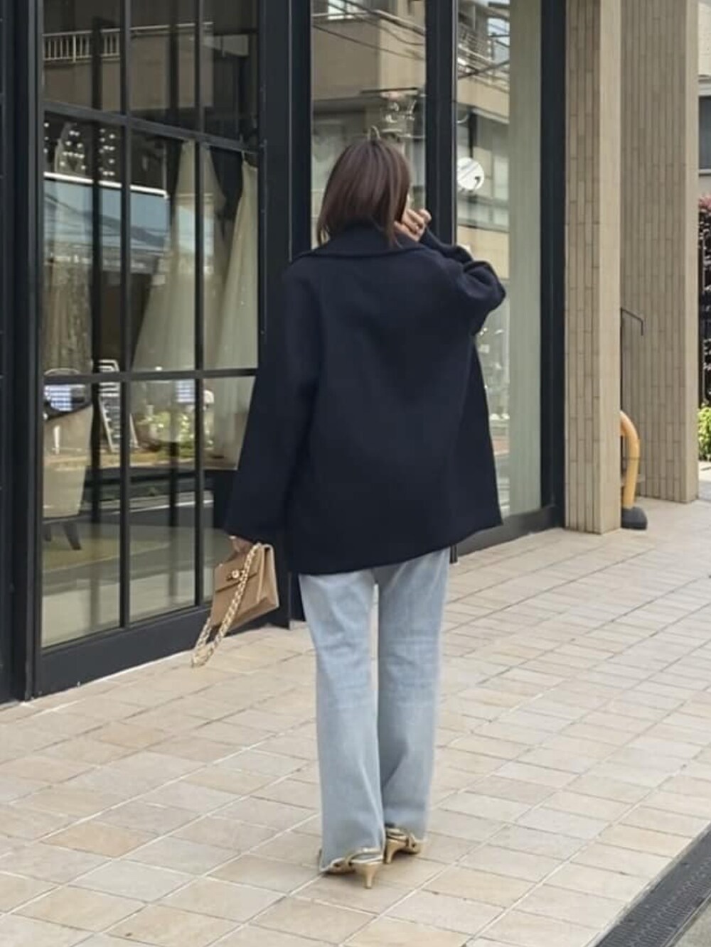 ブルー系のピーコート、ブルー系のデニムパンツ、ゴールド系のパンプスを着用したレディースの冬コーディネートの3枚目の写真