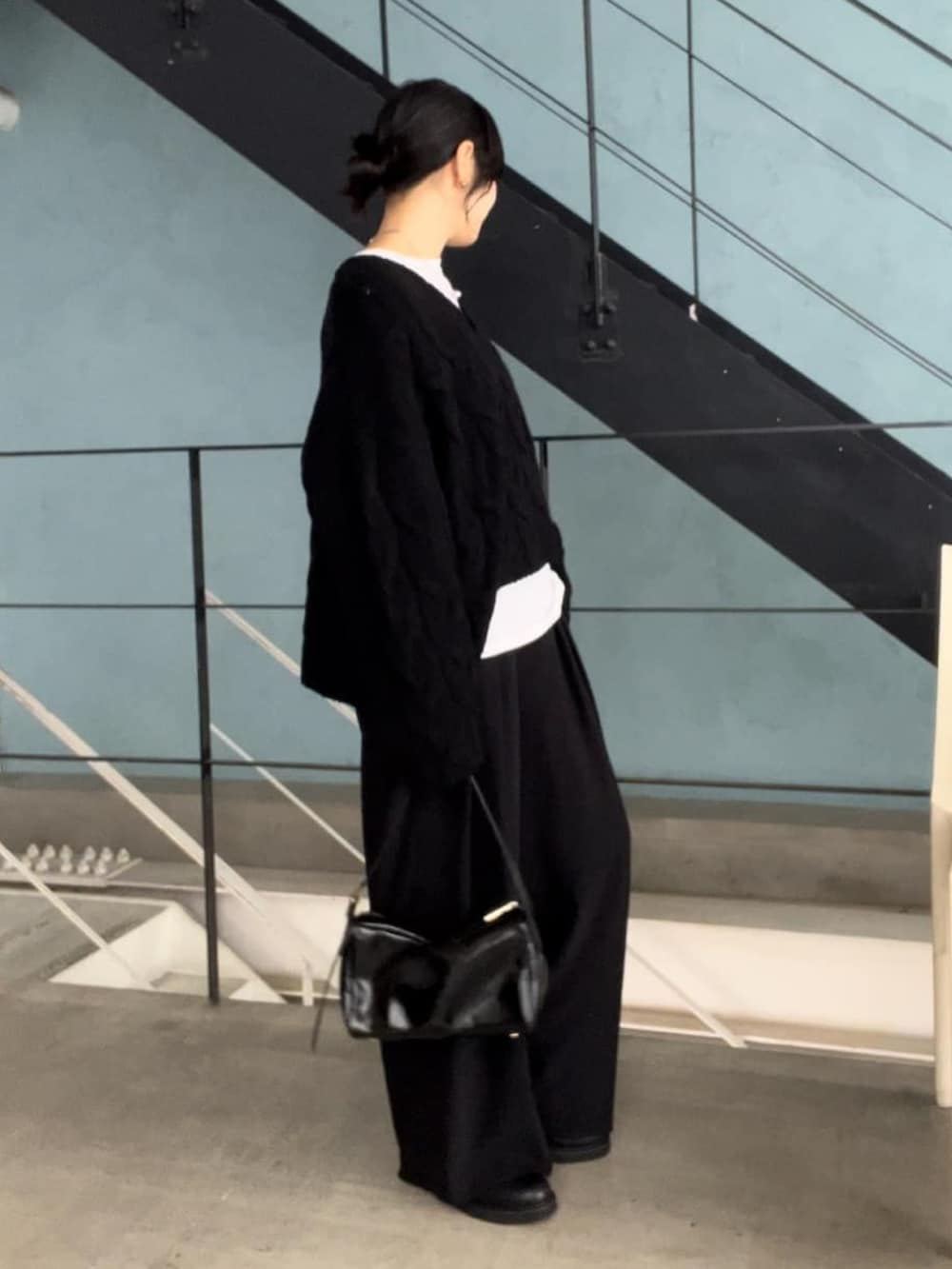 ブラック系のニット/セーター、ブラック系のスラックス、ブラック系のショルダーバッグを着用したレディースの秋コーディネートの2枚目の写真