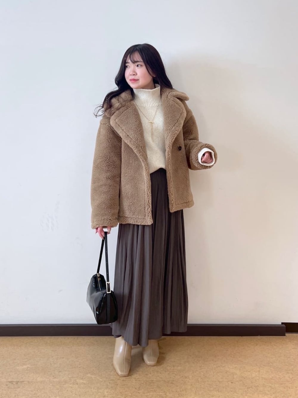 ホワイト系のニット/セーター、ベージュ系のその他アウター、グリーン系のスカートを着用したレディースの秋コーディネートの2枚目の写真