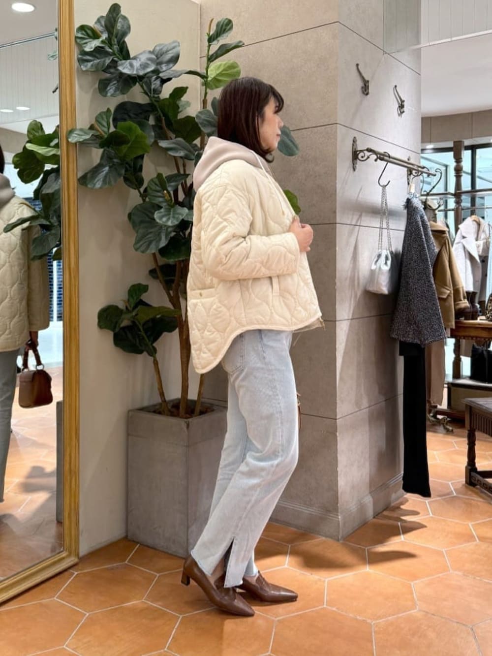 グレー系のニット/セーター、ホワイト系のダウンジャケット/コート、ブルー系のデニムパンツを着用したレディースの秋コーディネートの2枚目の写真