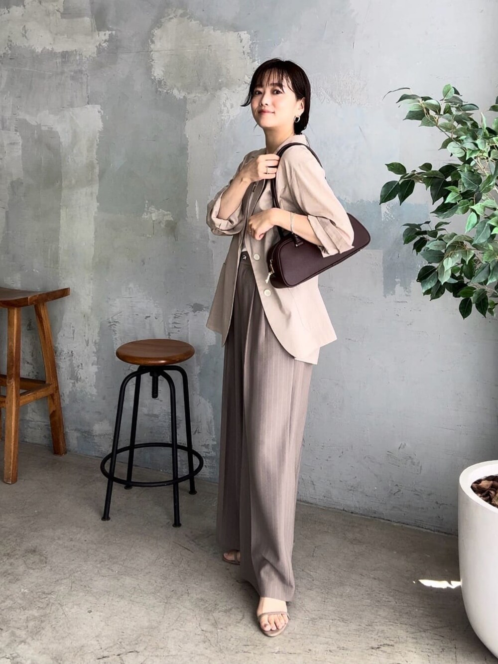ベージュ系のテーラードジャケット、ブラウン系のショルダーバッグ、ベージュ系のスラックスを着用したレディースの夏コーディネートの2枚目の写真