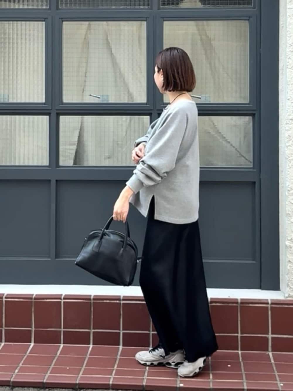 ブラック系のボストンバッグ、ブラック系のスカート、グレー系のテーラードジャケットを着用したレディースの冬コーディネートの3枚目の写真