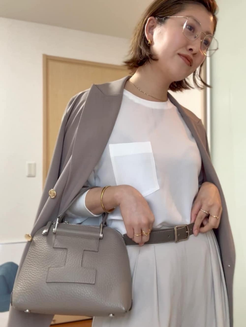 ホワイト系のシャツ/ブラウス、グレー系のスラックス、ブラウン系のテーラードジャケットを着用したレディースの春コーディネートの2枚目の写真