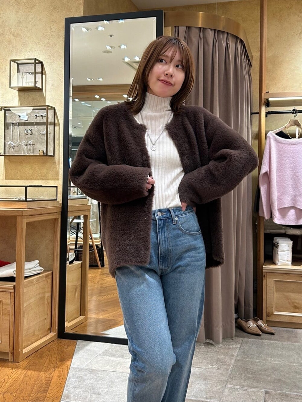 ホワイト系のニット/セーター、ブラウン系のカーディガン/ボレロ、ブルー系のデニムパンツを着用したレディースの秋コーディネートの4枚目の写真