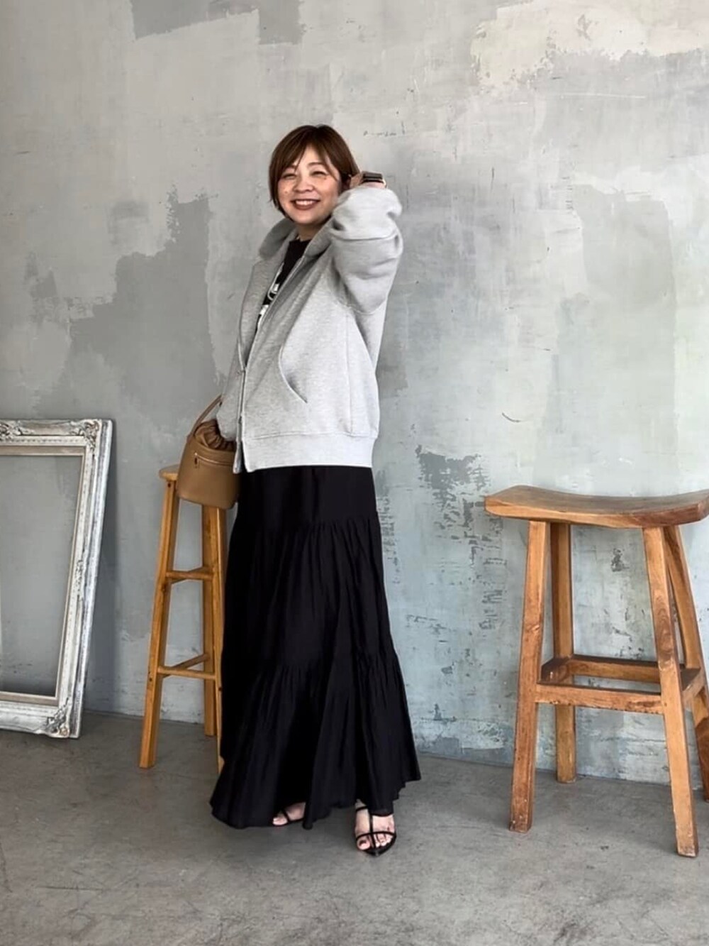 グレー系のパーカー、イエロー系のハンドバッグ、ブラック系のサンダルを着用したレディースの夏コーディネートの2枚目の写真