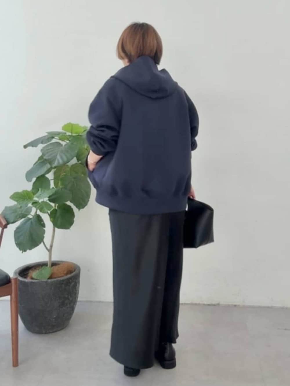 ブラック系のハンドバッグ、ブラック系のスカート、ブラック系のブーツを着用したレディースの冬コーディネートの2枚目の写真