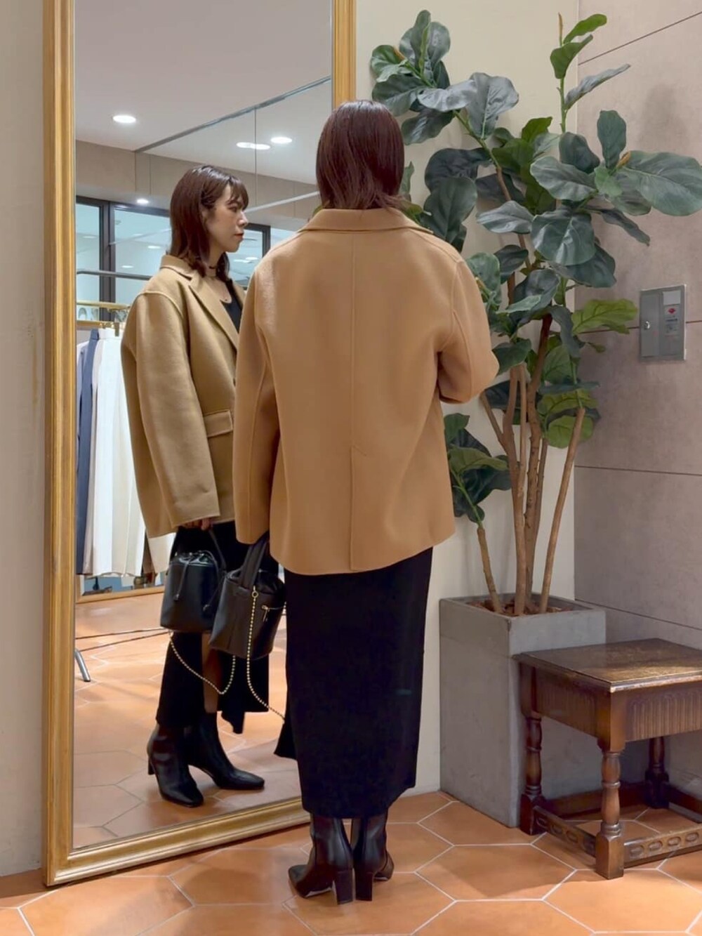 イエロー系のテーラードジャケット、ブラック系のワンピース、ブラック系のハンドバッグを着用したレディースの秋コーディネートの3枚目の写真