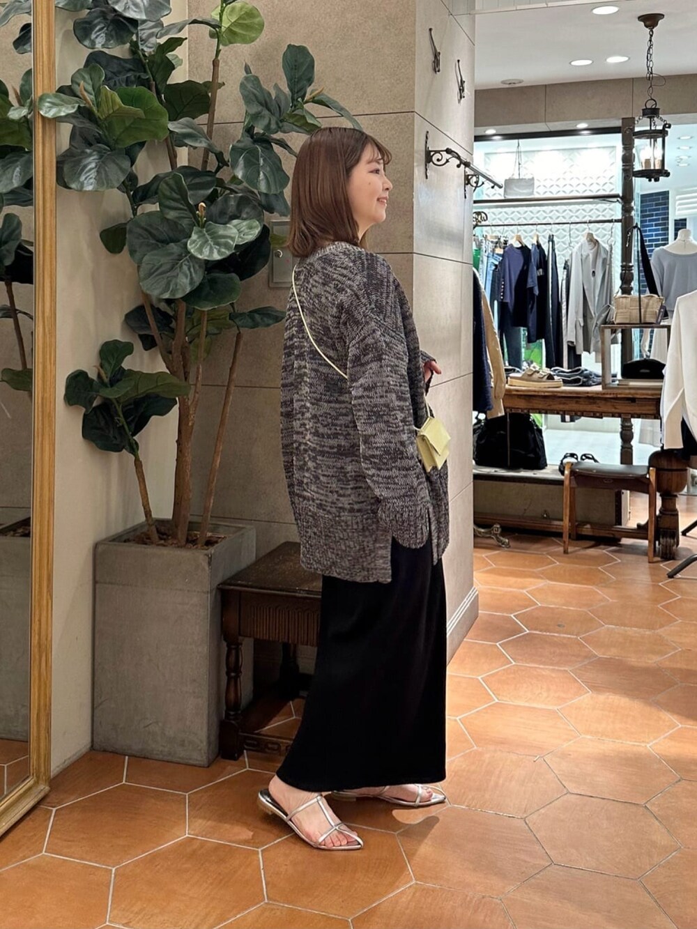 グレー系のカーディガン/ボレロ、ブラック系のワンピース、シルバー系のサンダルを着用したレディースの春コーディネートの2枚目の写真