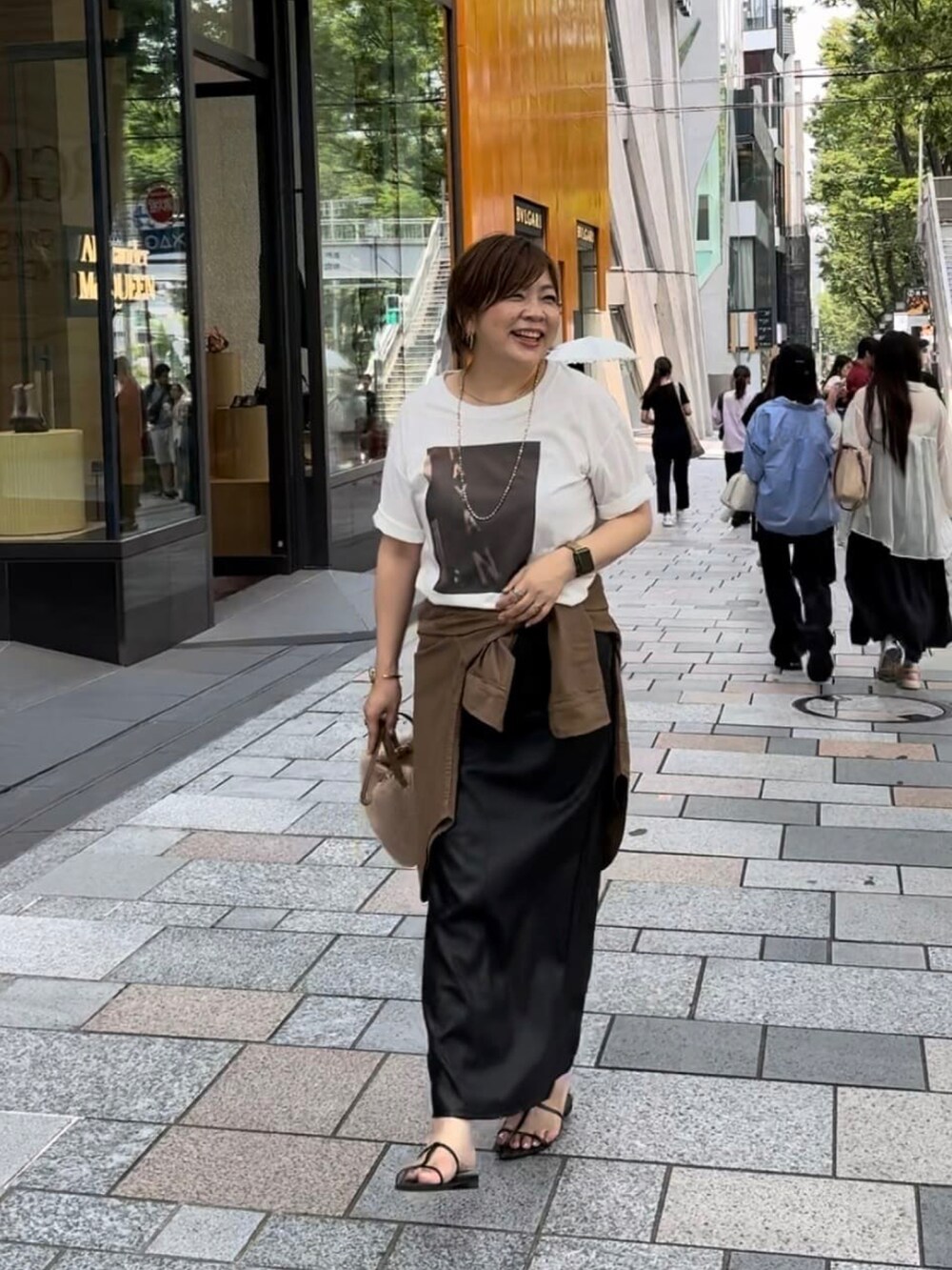 ブラック系のTシャツ/カットソー、ベージュ系のハンドバッグ、ブラック系のサンダルを着用したレディースの夏コーディネートの2枚目の写真