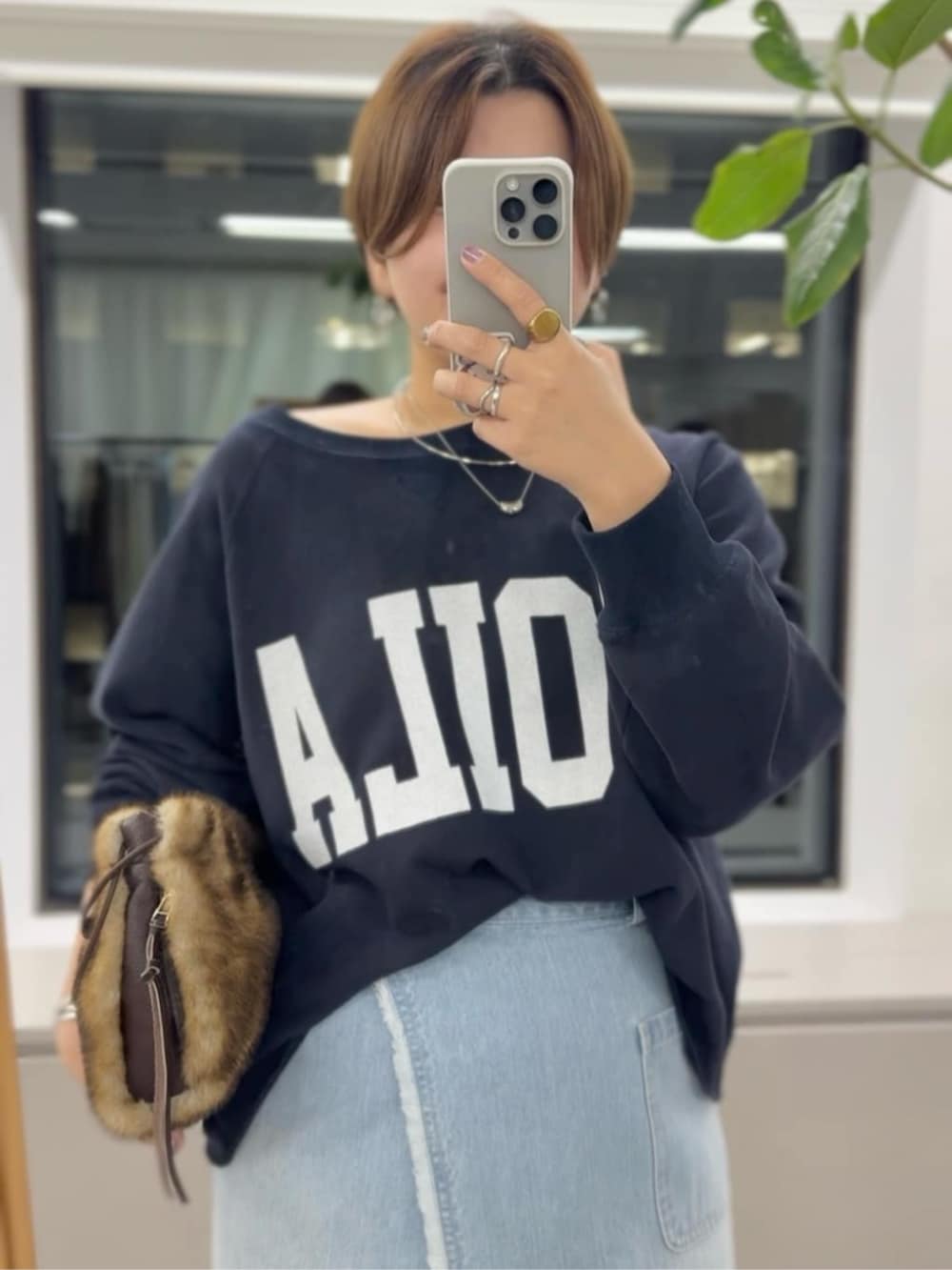 イエロー系のハンドバッグ、ブラック系のブーツ、ブルー系のスウェットを着用したレディースの秋コーディネートの2枚目の写真