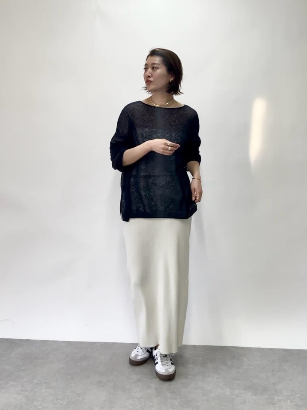 ブルー系のニット/セーター、ホワイト系のスカート、シルバー系のネックレスを着用したレディースの春コーディネートの2枚目の写真