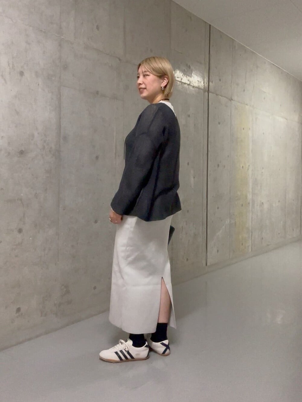 グレー系のニット/セーター、グレー系のスカート、ブラック系のハンドバッグを着用したレディースの冬コーディネートの3枚目の写真