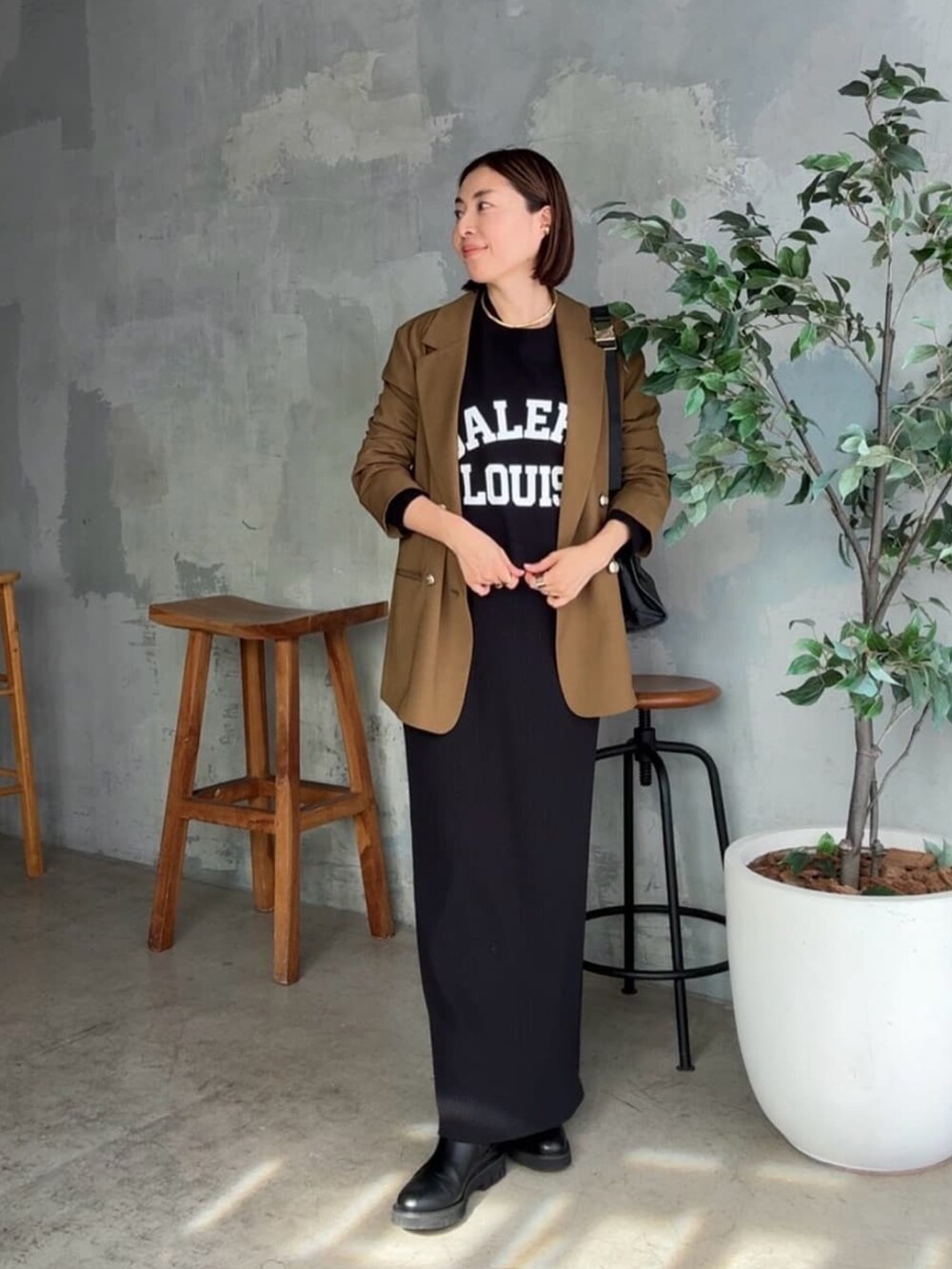 ブラック系のスウェット、ブラウン系のテーラードジャケット、ブラック系のワンピースを着用したレディースの秋コーディネートの3枚目の写真