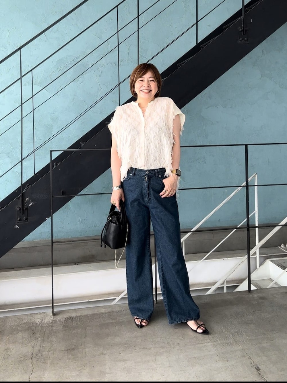 ホワイト系のシャツ/ブラウス、ブルー系のデニムパンツ、ブラック系のハンドバッグを着用したレディースの夏コーディネートの3枚目の写真