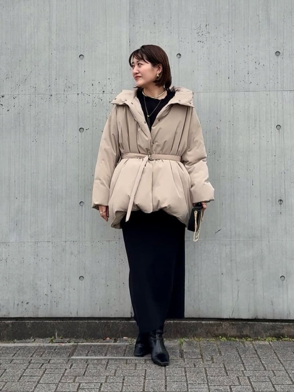 ブルー系のニット/セーター、ブルー系のスカート、ブラック系のショルダーバッグを着用したレディースの冬コーディネートの4枚目の写真