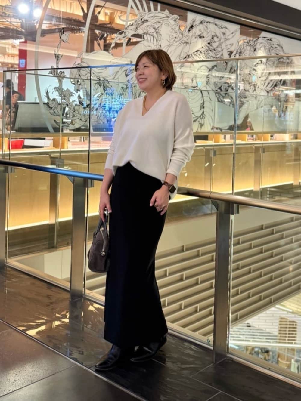 ホワイト系のニット/セーター、ブラック系のスカート、ゴールド系のネックレスを着用したレディースの冬コーディネートの5枚目の写真