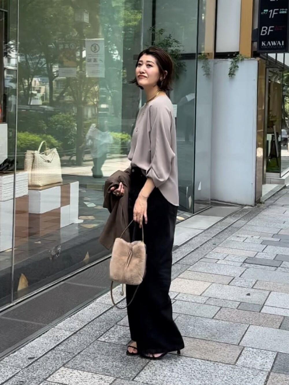 グレー系のシャツ/ブラウス、ブラック系のデニムパンツ、ベージュ系のハンドバッグを着用したレディースの夏コーディネートの3枚目の写真