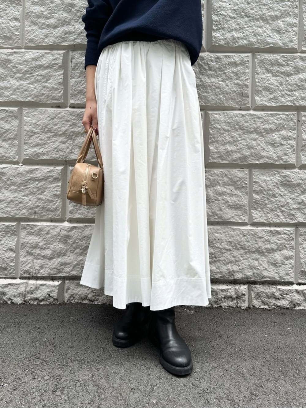 ホワイト系のスカート、ブルー系のニット/セーター、ブラック系のブーツを着用したレディースの秋コーディネートの5枚目の写真