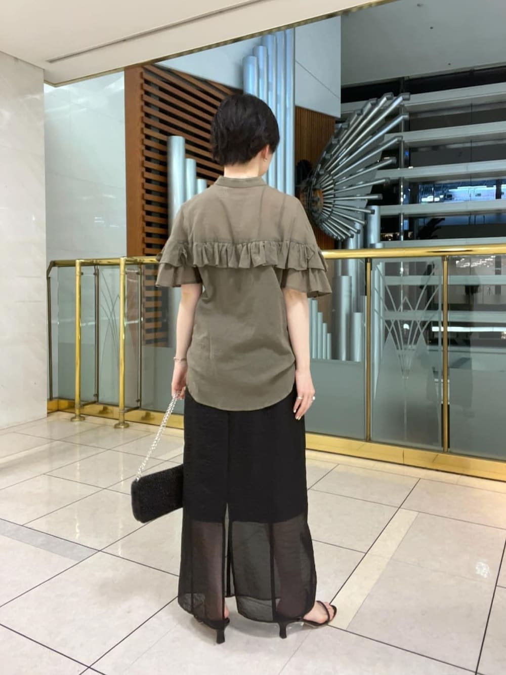 グリーン系のシャツ/ブラウス、ブラック系のショルダーバッグ、ブラック系のサンダルを着用したレディースの夏コーディネートの3枚目の写真