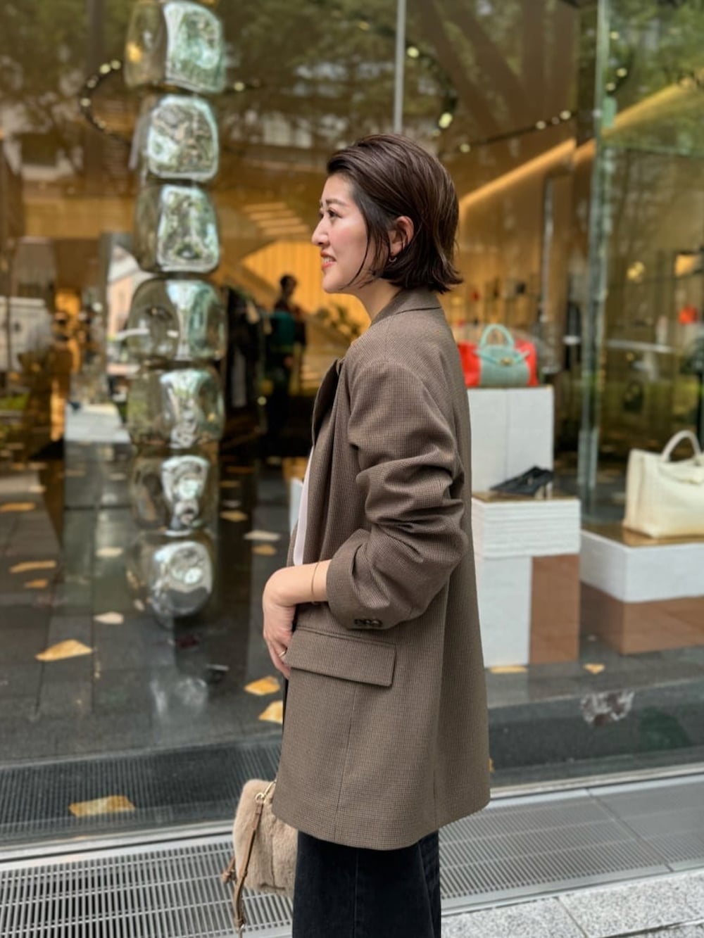 ブラック系のデニムパンツ、ベージュ系のハンドバッグ、ブラック系のサンダルを着用したレディースの夏コーディネートの4枚目の写真