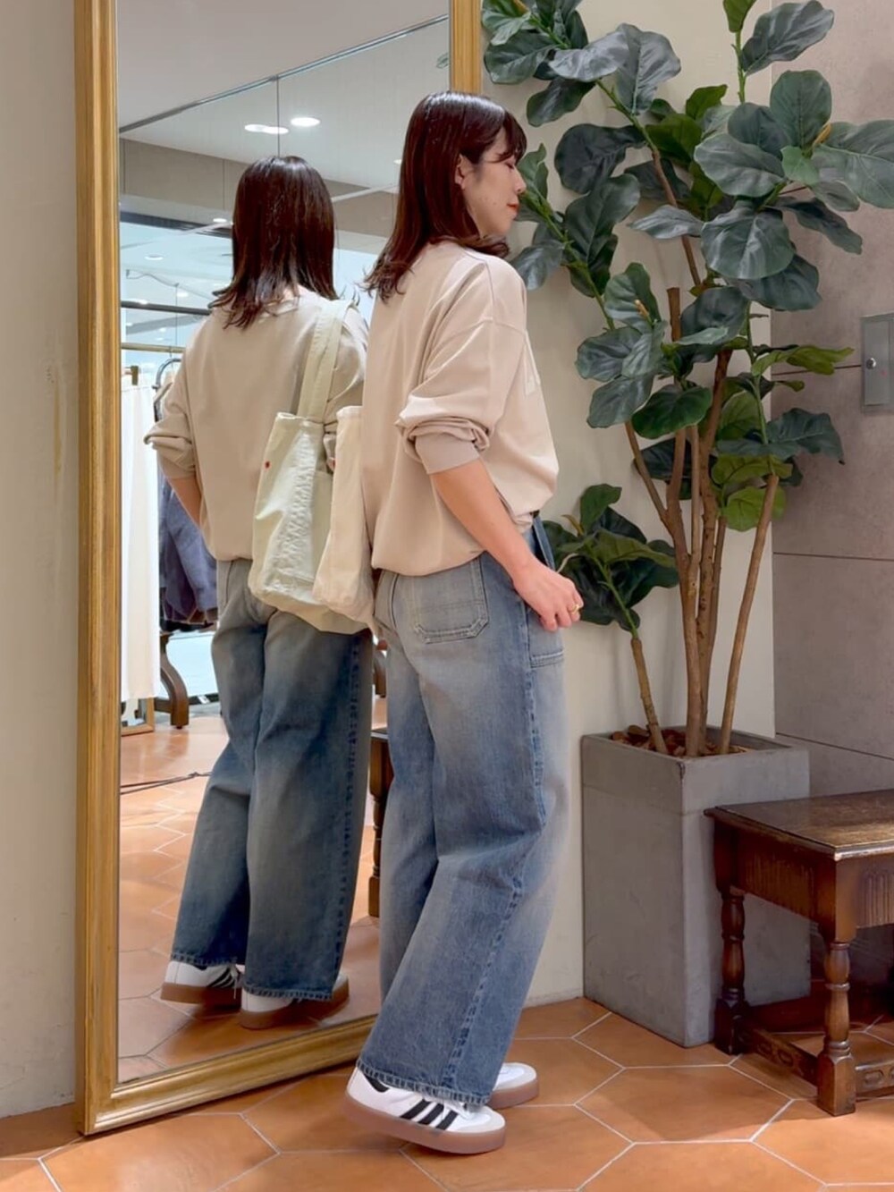 ベージュ系のスウェット、ホワイト系のトートバッグ、ブルー系のデニムパンツを着用したレディースの冬コーディネートの3枚目の写真