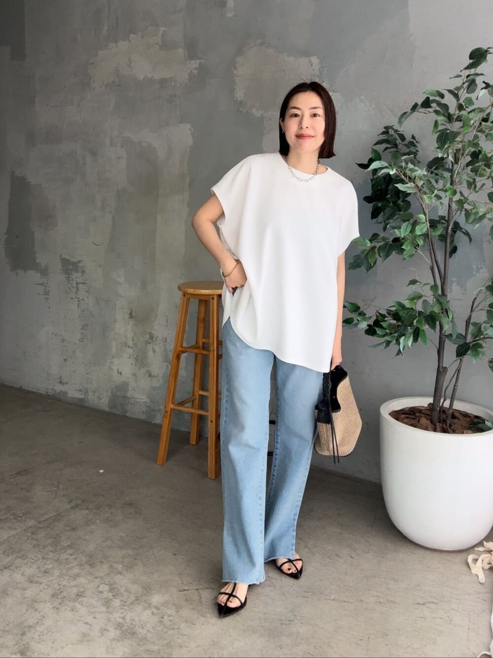 ブルー系のデニムパンツ、ブラック系のサンダル、ホワイト系のハンドバッグを着用したレディースの春コーディネートの5枚目の写真