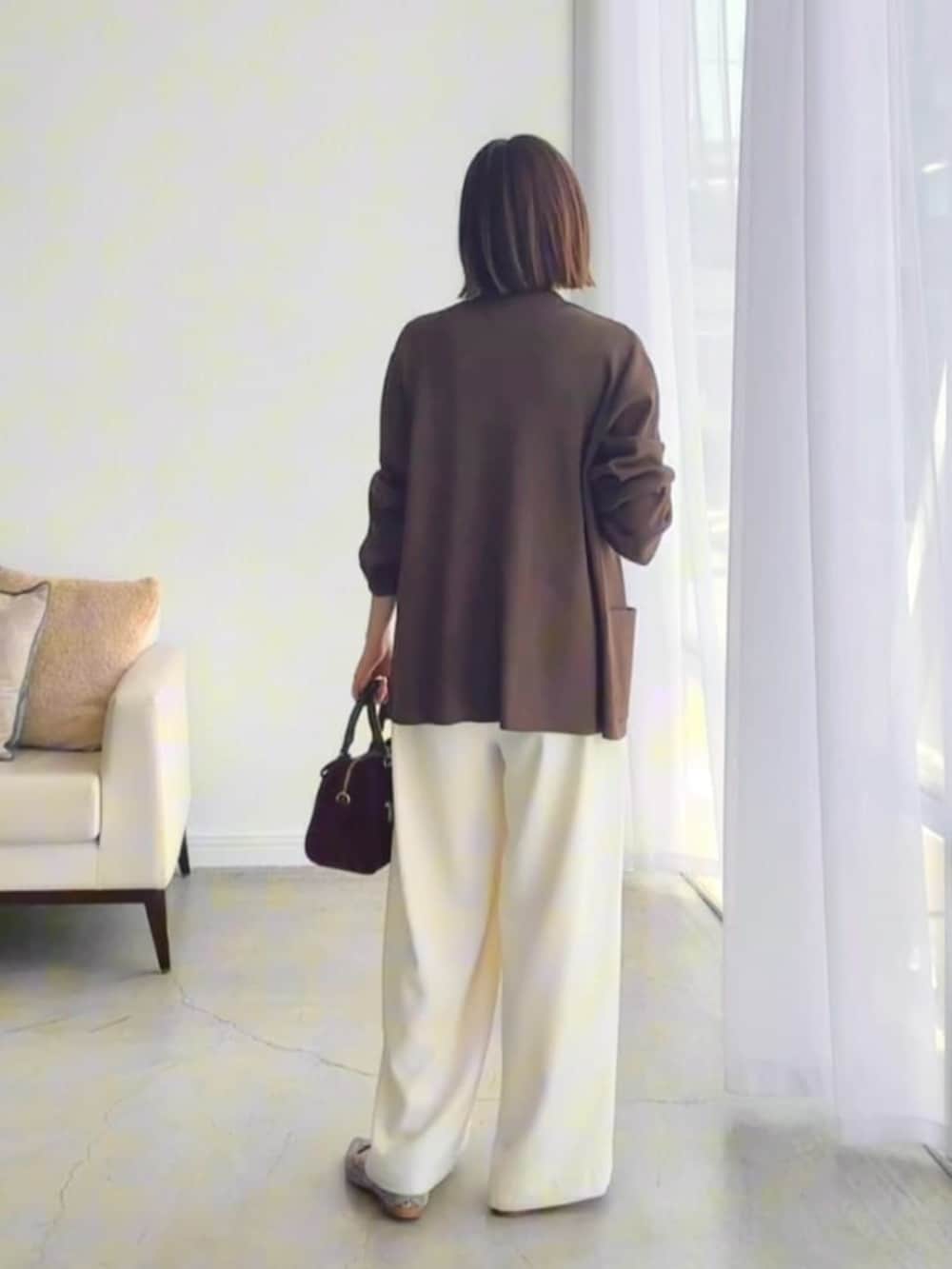 ホワイト系のスラックス、グレー系のパンプス、ホワイト系のキャミソールを着用したレディースの夏コーディネートの3枚目の写真