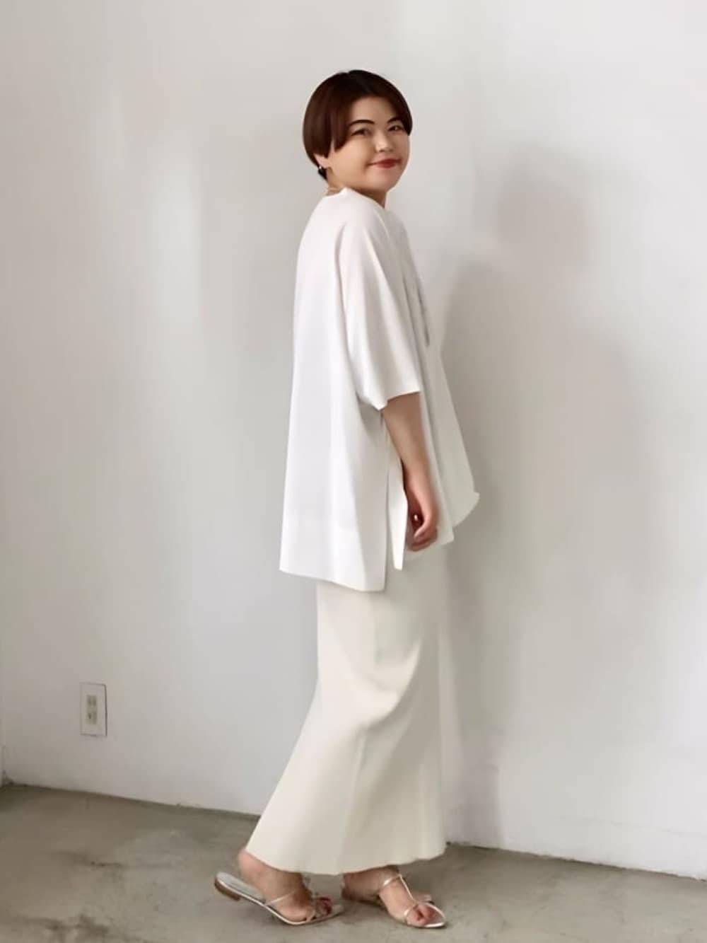 ブラック系のTシャツ/カットソー、ホワイト系のスカート、シルバー系のサンダルを着用したレディースの春コーディネートの2枚目の写真