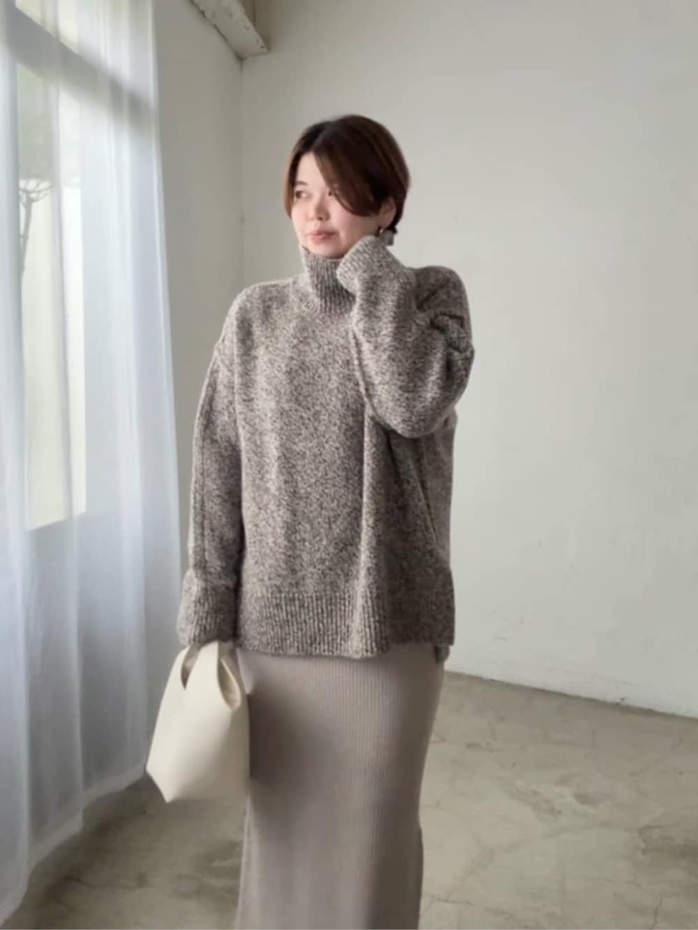 ホワイト系のハンドバッグ、ブラウン系のニット/セーター、ベージュ系のワンピースを着用したレディースの秋コーディネートの4枚目の写真