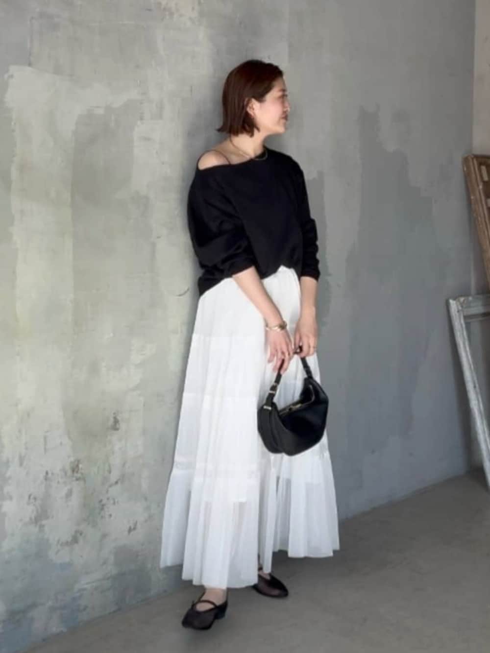 ブラック系のその他シューズ、ブラック系のショルダーバッグ、ホワイト系のスカートを着用したレディースの春コーディネートの2枚目の写真