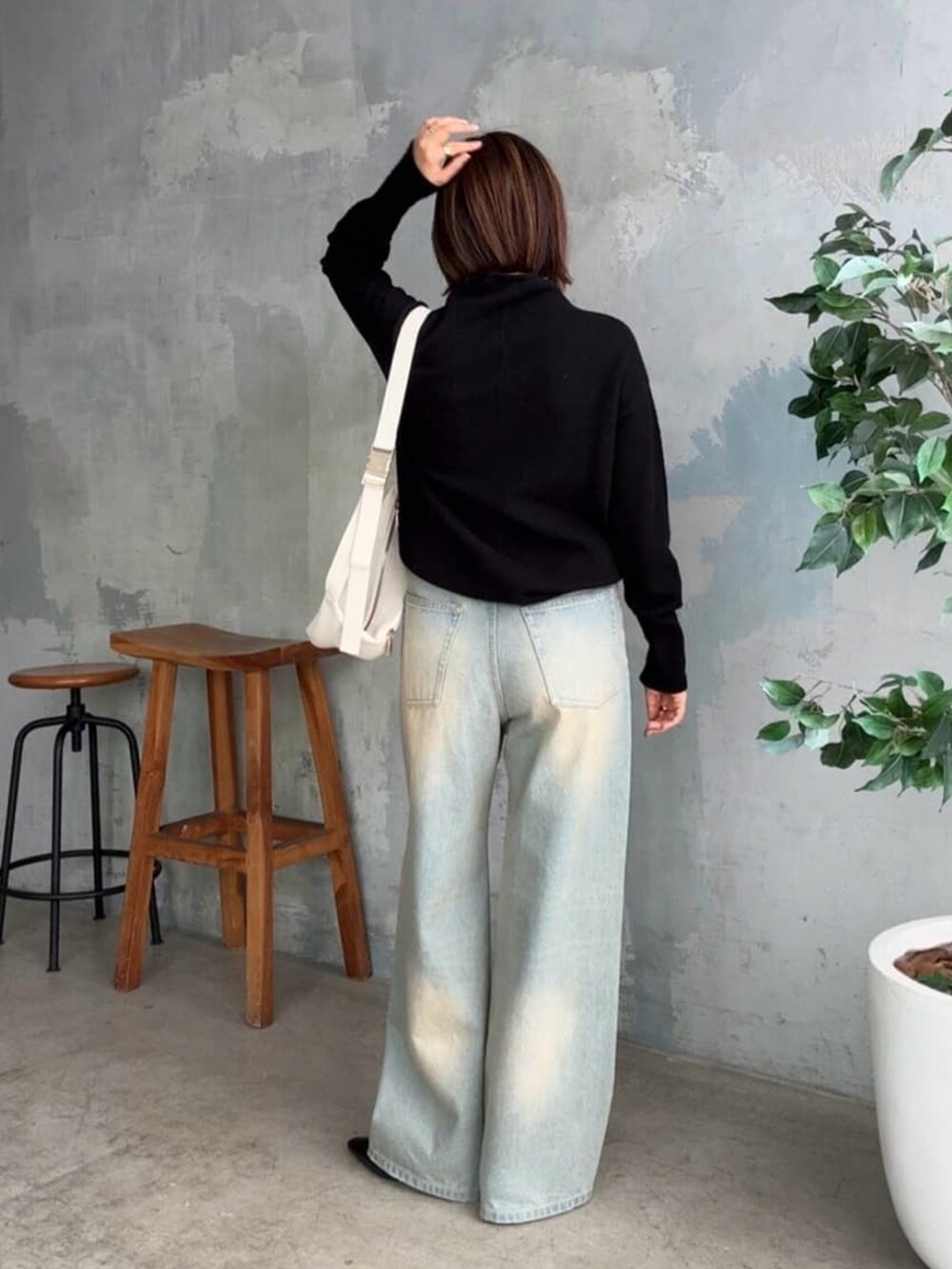 ブラック系のニット/セーター、ブルー系のデニムパンツ、ブラック系のローファーを着用したレディースの秋コーディネートの3枚目の写真