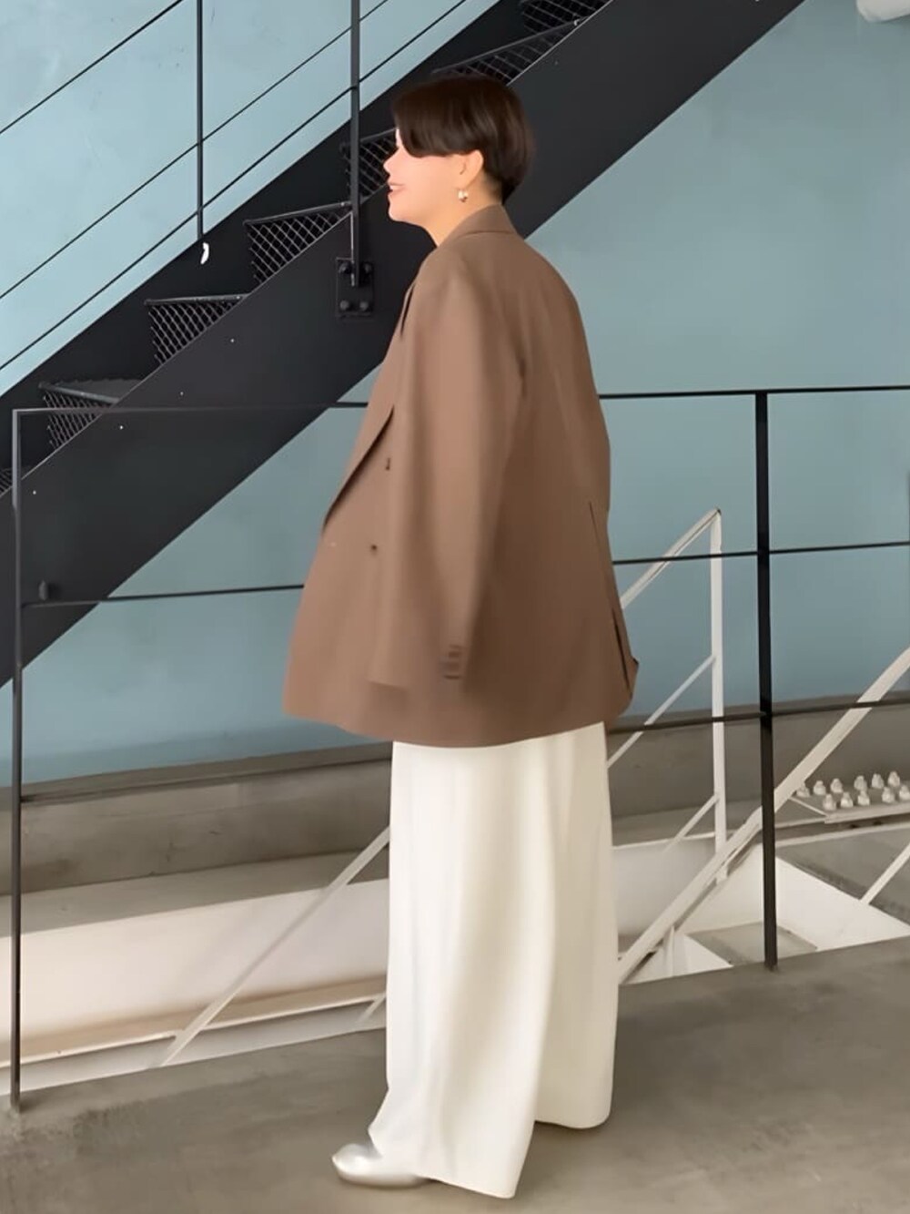 ブラウン系のテーラードジャケット、ベージュ系のニット/セーター、ホワイト系のスラックスを着用したレディースの秋コーディネートの2枚目の写真