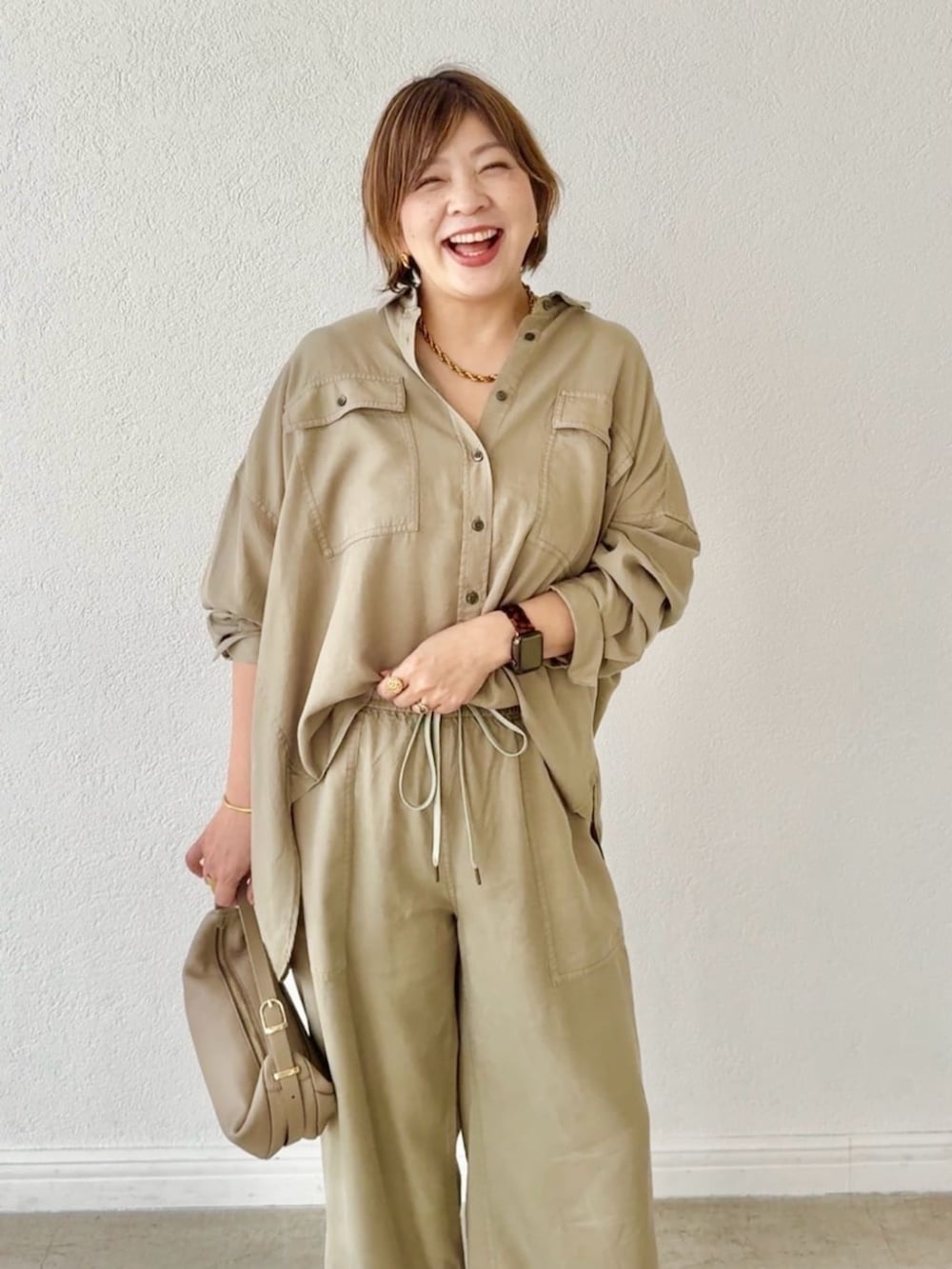 ベージュ系のその他シューズ、グリーン系のシャツ/ブラウス、ベージュ系のショルダーバッグを着用したレディースの春コーディネートの4枚目の写真