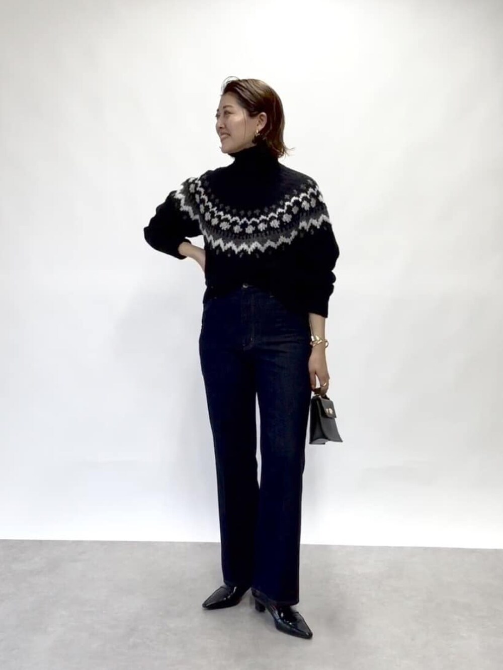 イエロー系のピーコート、ブルー系のデニムパンツ、ブラック系のニット/セーターを着用したレディースの冬コーディネートの2枚目の写真