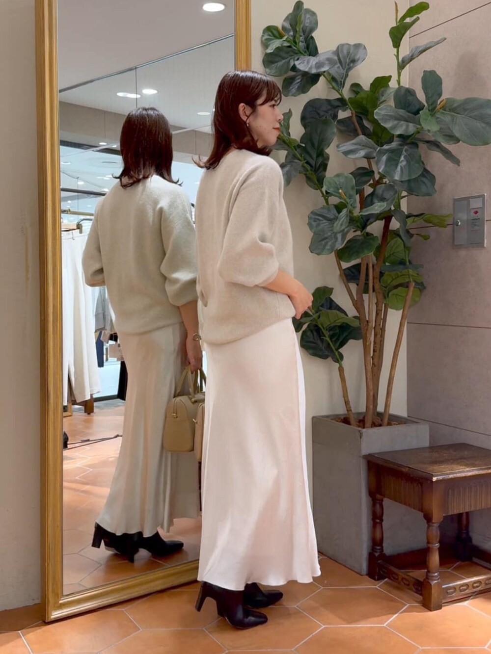 ベージュ系のボストンバッグ、ベージュ系のカーディガン/ボレロ、ベージュ系のスカートを着用したレディースの秋コーディネートの2枚目の写真