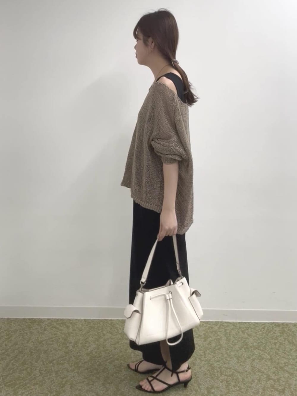 ブラック系のワンピース、ブラウン系のニット/セーター、ホワイト系のショルダーバッグを着用したレディースの春コーディネートの2枚目の写真