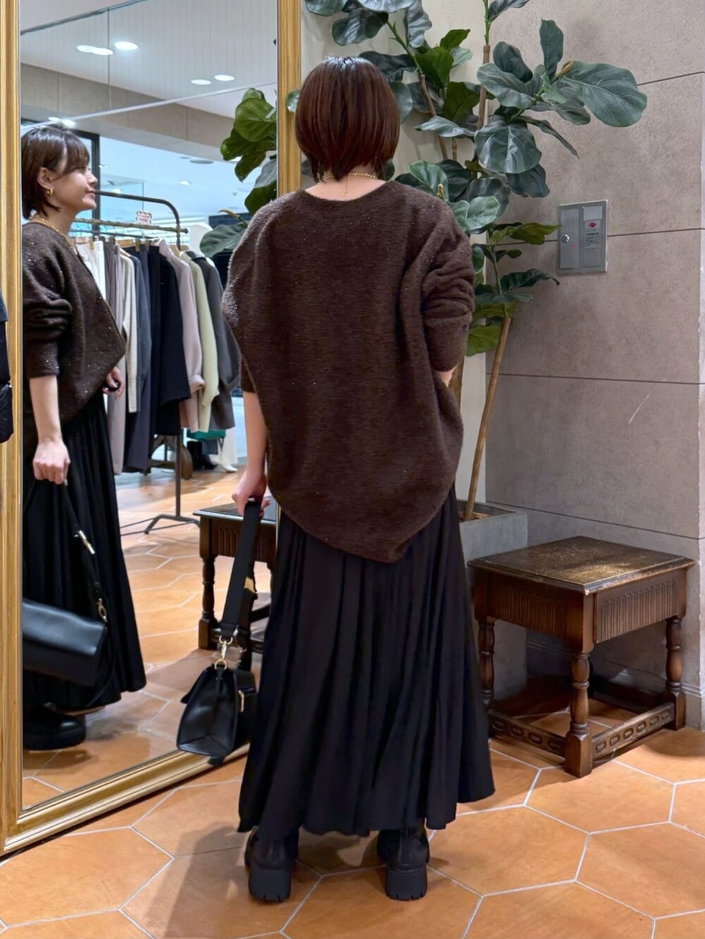 ブラウン系のカーディガン/ボレロ、ブラック系のスカート、ブラック系のショルダーバッグを着用したレディースの冬コーディネートの3枚目の写真