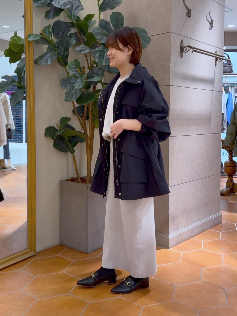 グレー系のニット/セーター、グレー系のスカート、ブラック系のマウンテンパーカーを着用したレディースの冬コーディネートの2枚目の写真