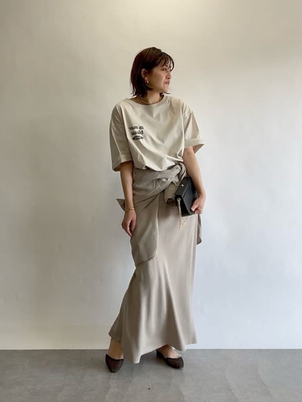 グレー系のスカート、ブラック系のショルダーバッグ、ブラック系のパンプスを着用したレディースの冬コーディネートの2枚目の写真