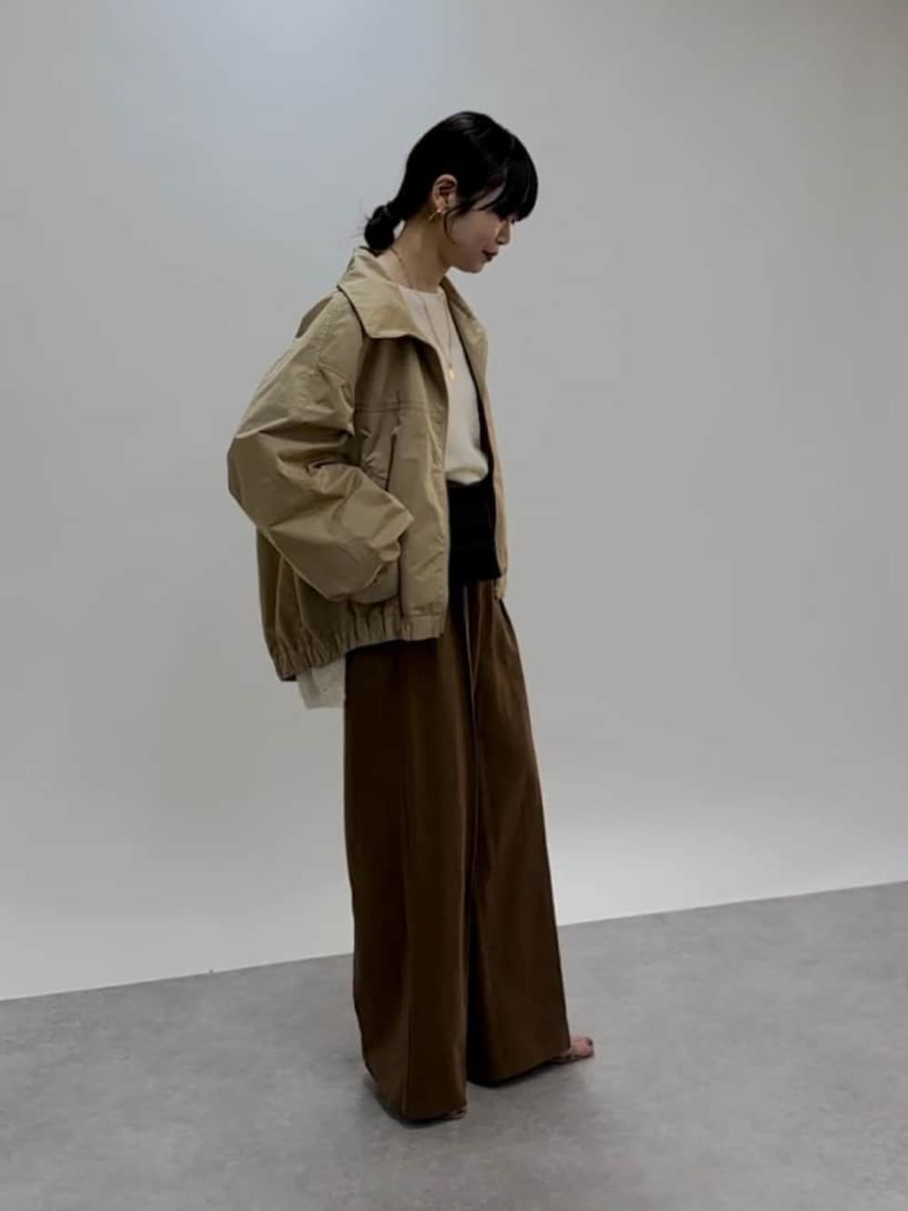 ホワイト系のニット/セーター、ベージュ系のブルゾン、ブラウン系のその他パンツを着用したレディースの春コーディネートの2枚目の写真