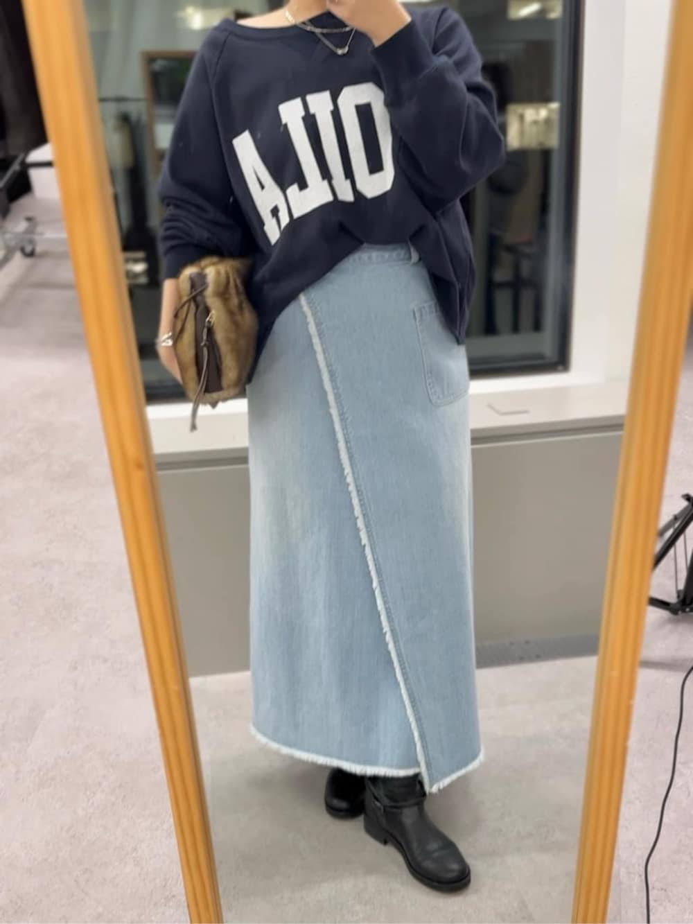 イエロー系のハンドバッグ、ブラック系のブーツ、ブルー系のスウェットを着用したレディースの秋コーディネートの3枚目の写真