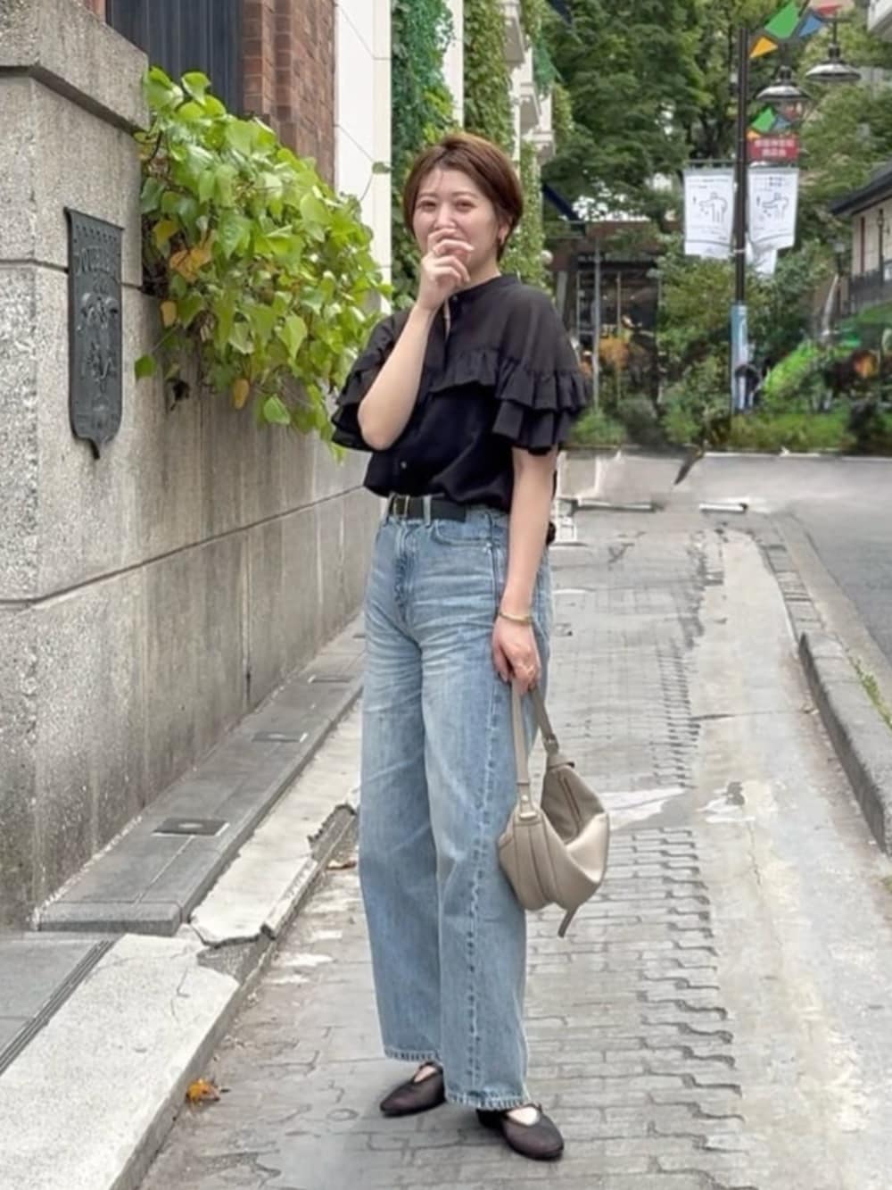 ブラック系のその他シューズ、ブルー系のデニムパンツ、ベージュ系のショルダーバッグを着用したレディースの春コーディネートの2枚目の写真