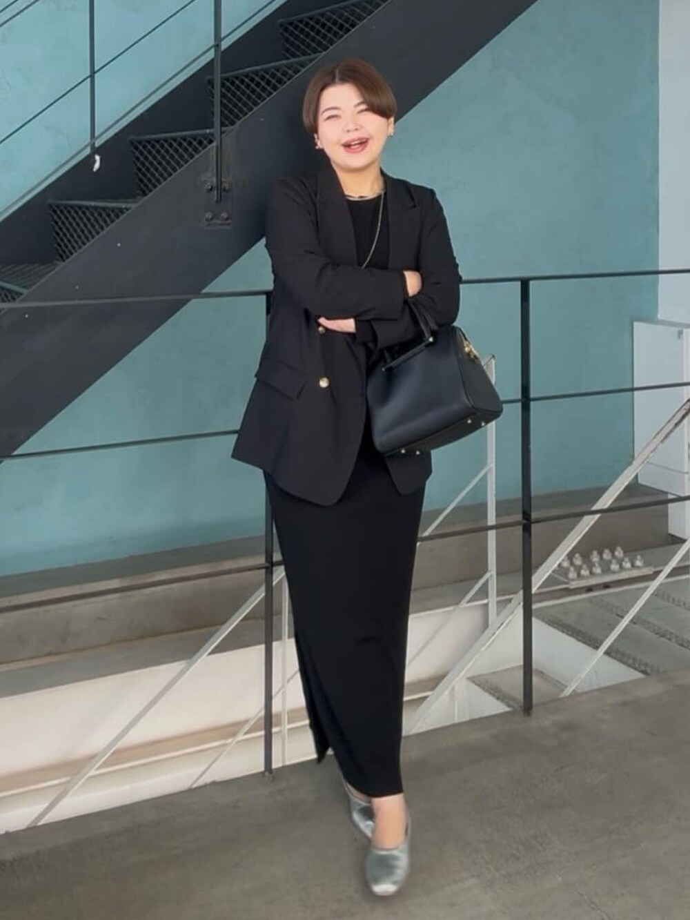 ブラック系のテーラードジャケット、ブラック系のボストンバッグ、ブラック系のワンピースを着用したレディースの冬コーディネートの2枚目の写真