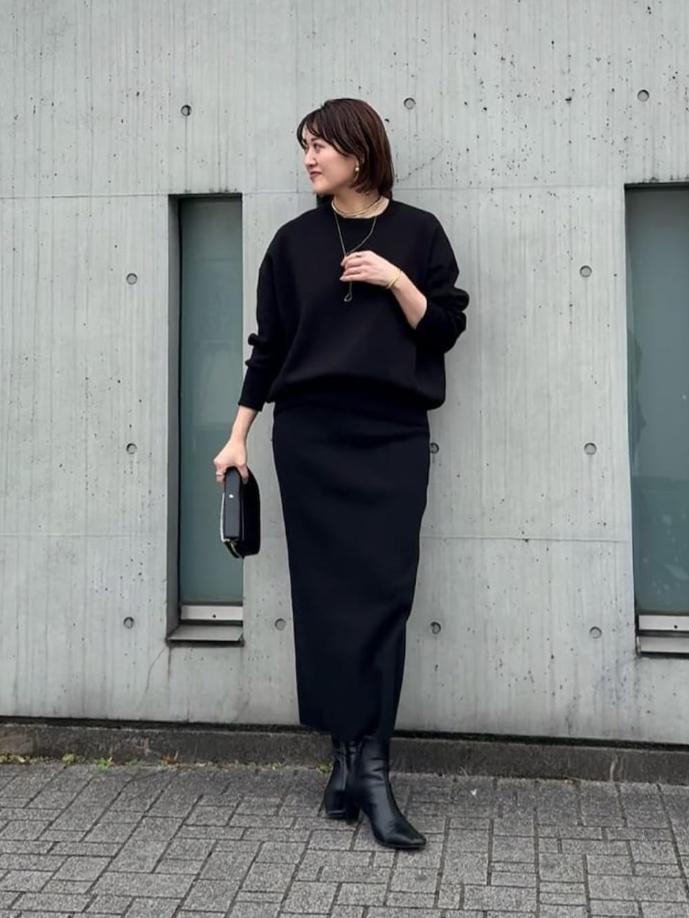 ブルー系のニット/セーター、ブルー系のスカート、ブラック系のショルダーバッグを着用したレディースの冬コーディネートの2枚目の写真