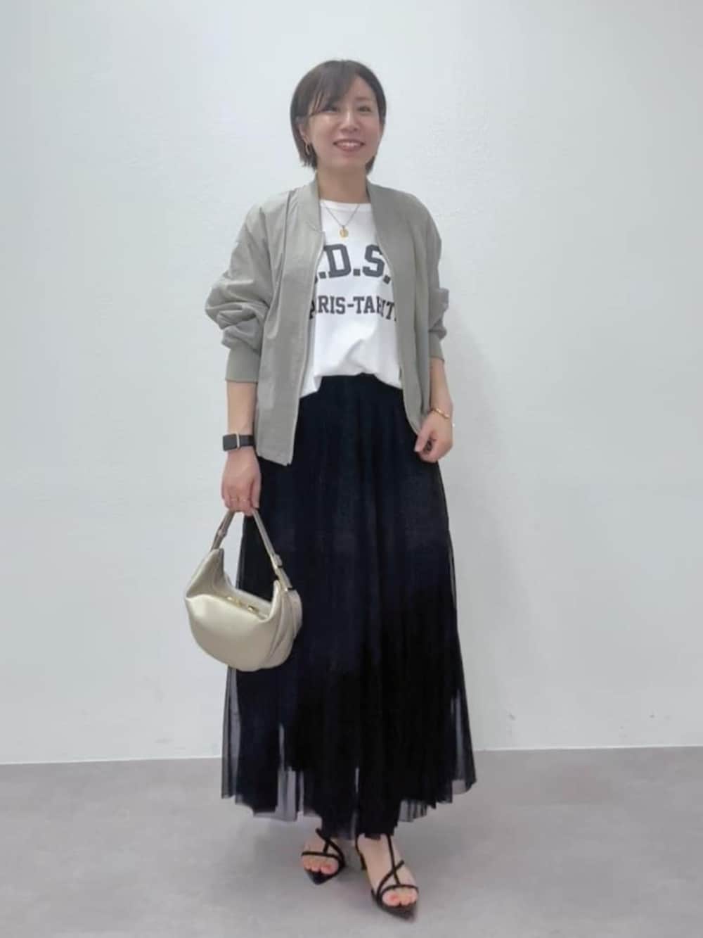 ブラック系のサンダル、ゴールド系のショルダーバッグ、グリーン系のブルゾンを着用したレディースの春コーディネートの2枚目の写真