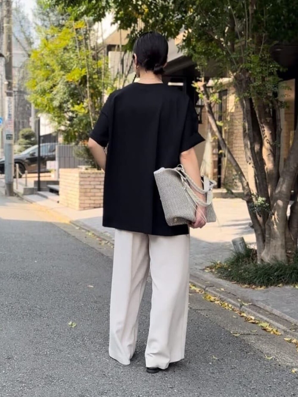 ブラック系のTシャツ/カットソー、グレー系のスラックス、ホワイト系のトートバッグを着用したレディースの春コーディネートの3枚目の写真