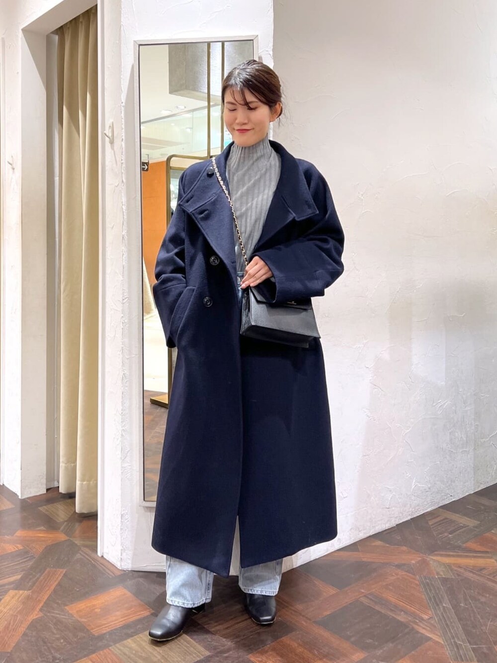 ブラック系のハンドバッグ、ブルー系のその他アウター、グレー系のニット/セーターを着用したレディースの冬コーディネートの2枚目の写真