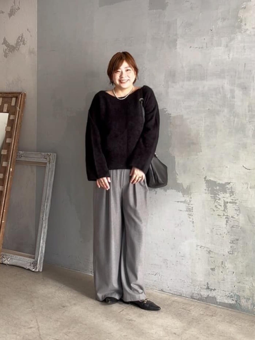 ブラック系のニット/セーター、グレー系のスラックスを着用したレディースの冬コーディネートの2枚目の写真