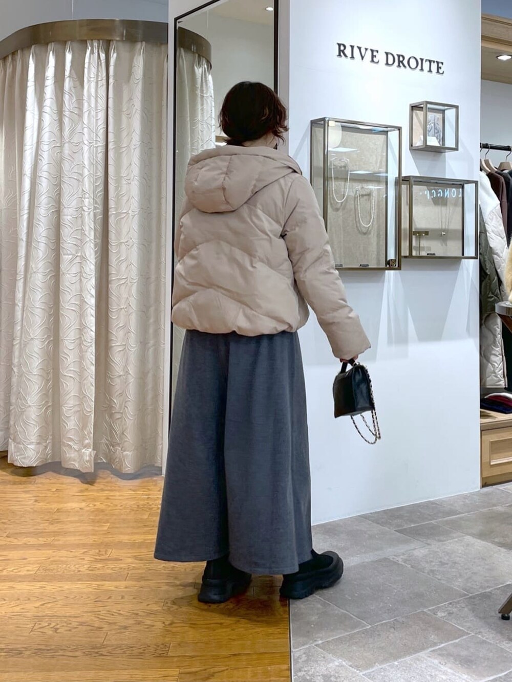 ブラック系のダウンジャケット/コート、グレー系のワンピース、ブラック系のブーツを着用したレディースの冬コーディネートの4枚目の写真