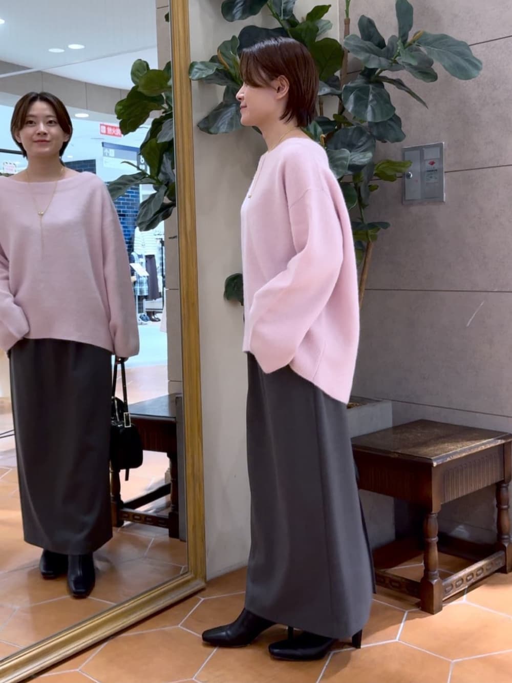 ピンク系のニット/セーター、グレー系のスカート、ブラック系のブーツを着用したレディースの秋コーディネートの2枚目の写真